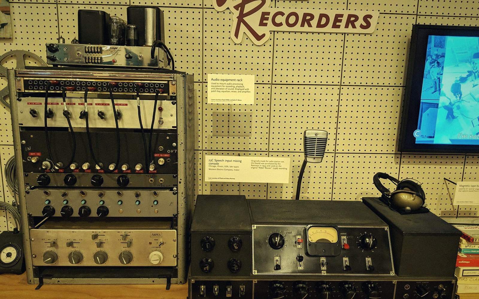 A mixing desk with faders set and tape reels behind