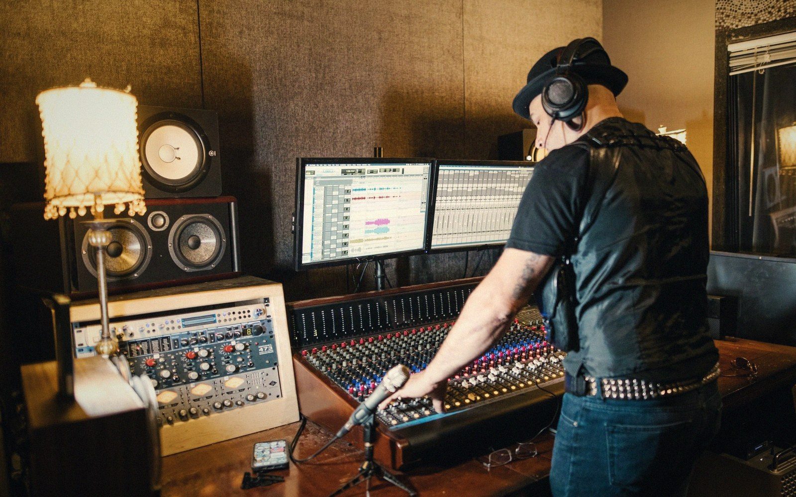 A man wearing headphones adjusts a mixing console in a recording studio